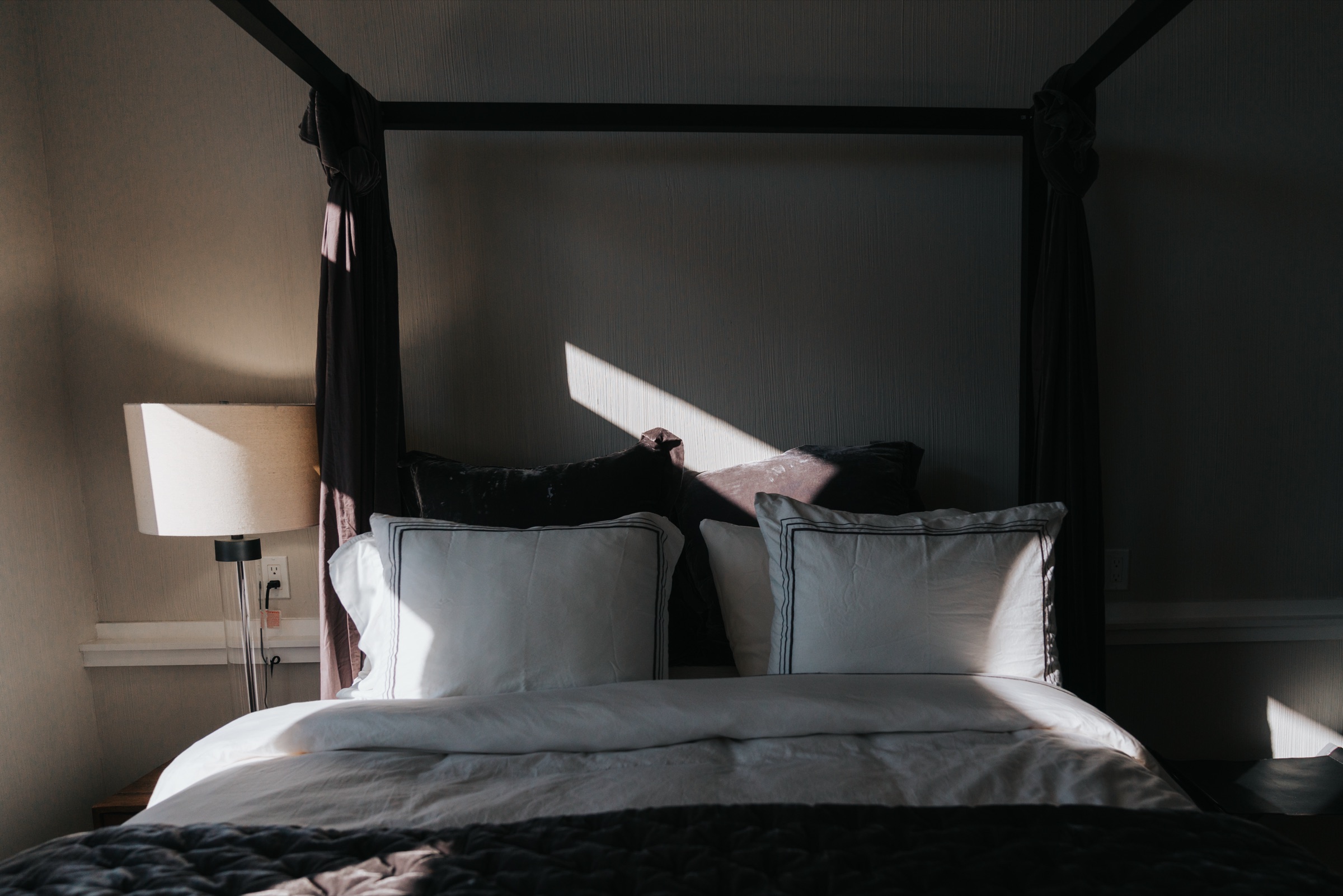 Bedroom with mountain peaks framed in the window directly behind a four-poster bed
