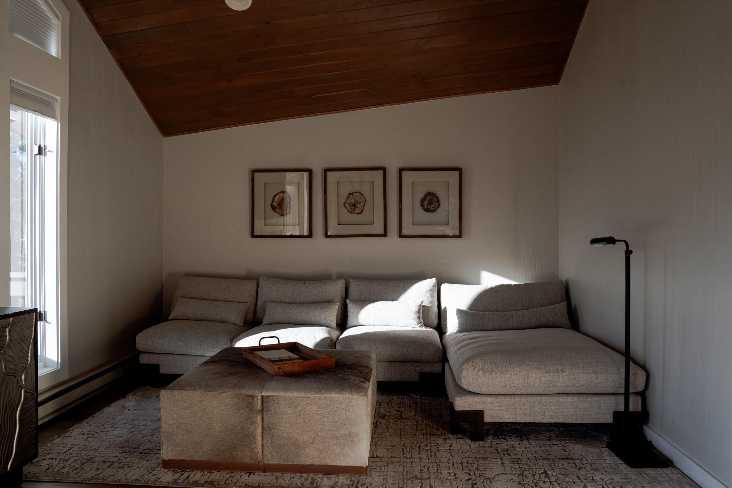Loft sitting nook with grey sectional, vaulted plank ceiling, and soft window light