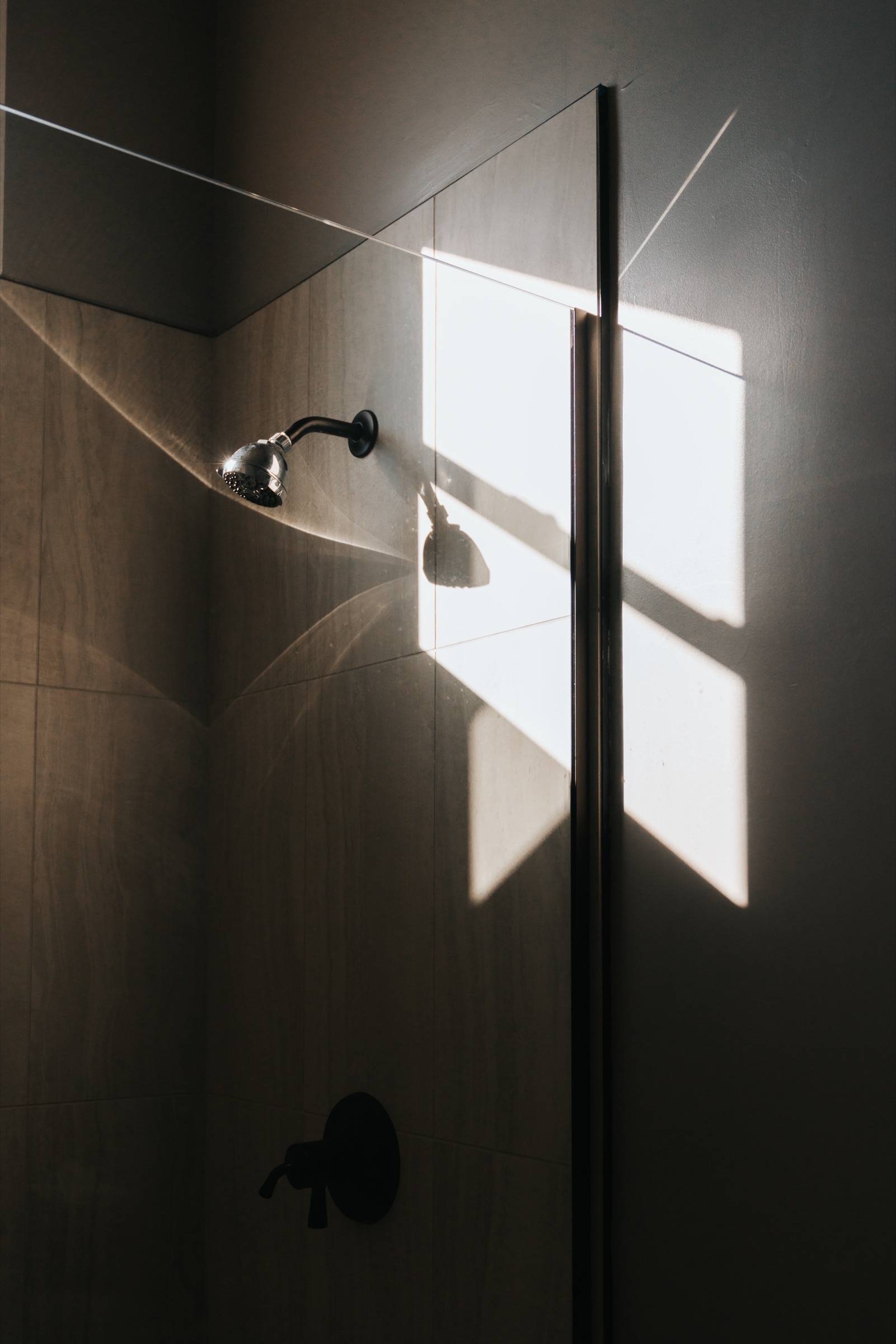 Stone shower with shaft of window light cutting across the wall