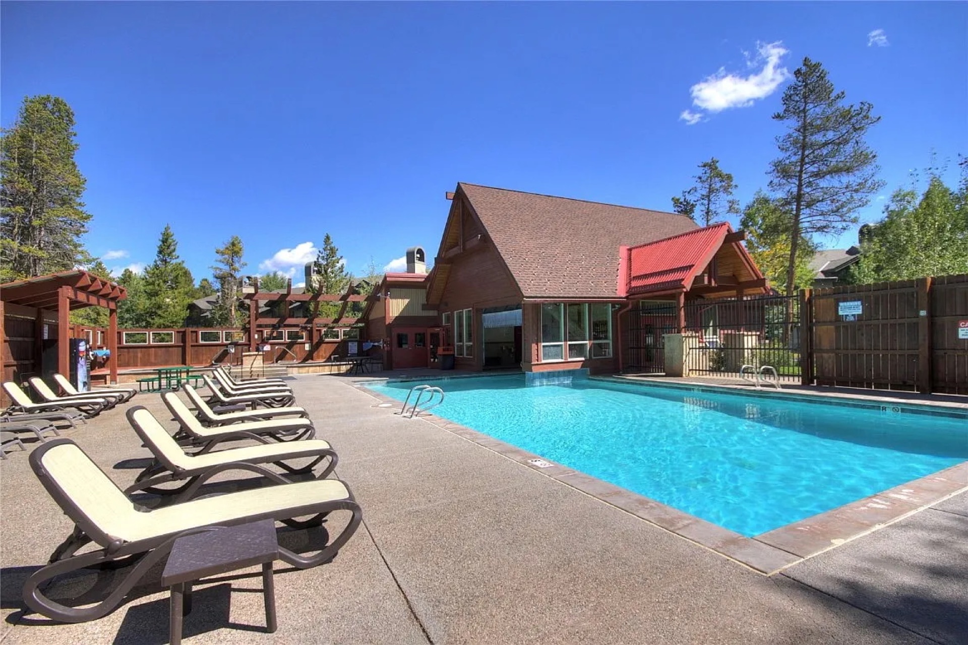 Heated outdoor pool with lounge chairs and A-frame clubhouse at Cedars Breckenridge