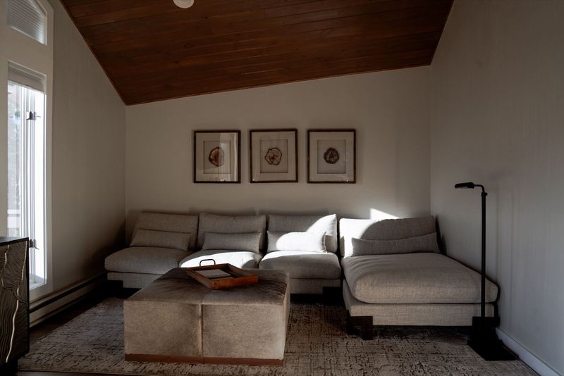 Loft sitting nook with grey sectional, vaulted plank ceiling, and soft window light